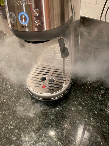 A Breville Bambino espresso machine steaming milk at home